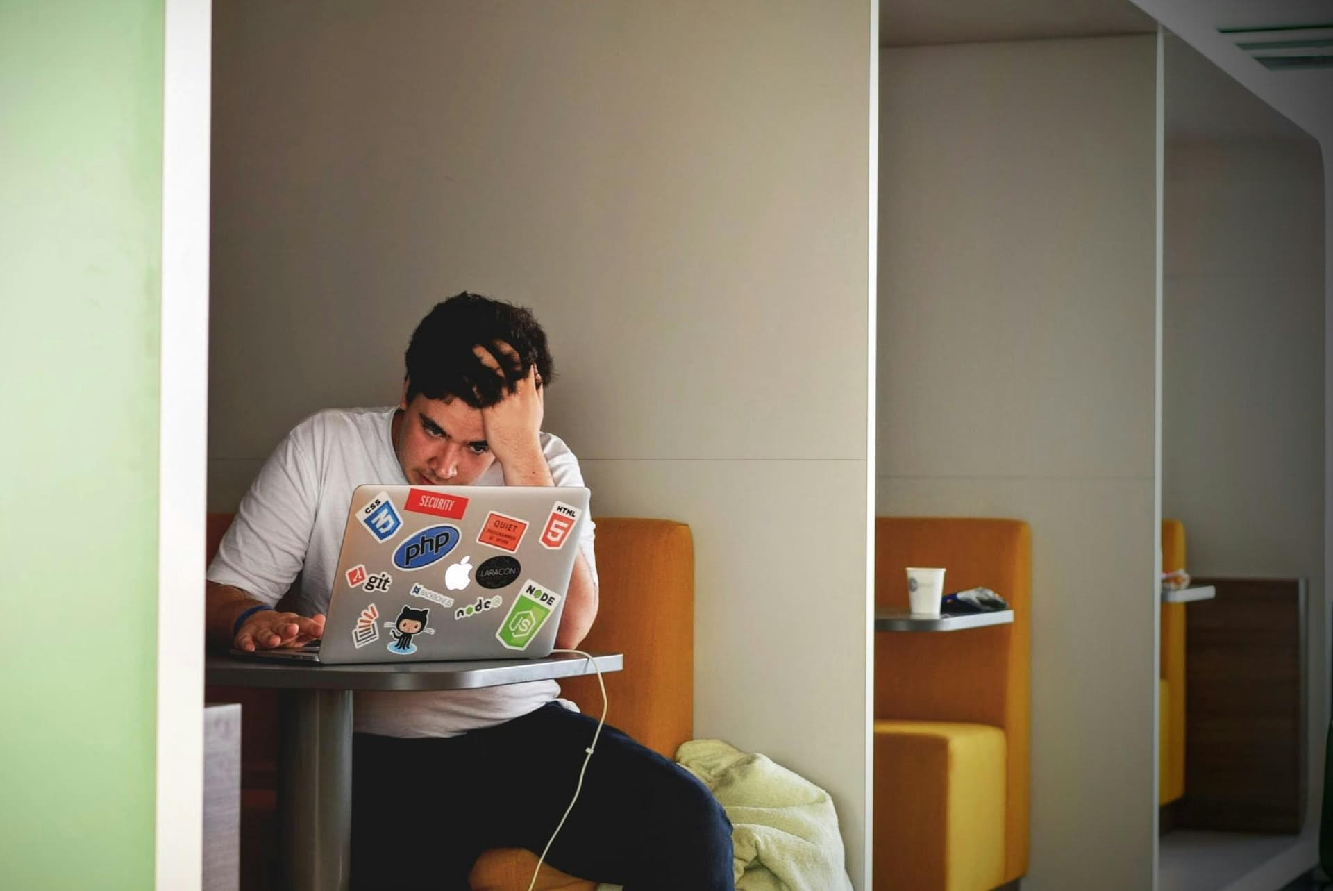 Profissional com a mão na cabeça diante do notebook, sinal de sobrecarga no trabalho do conhecimento.
