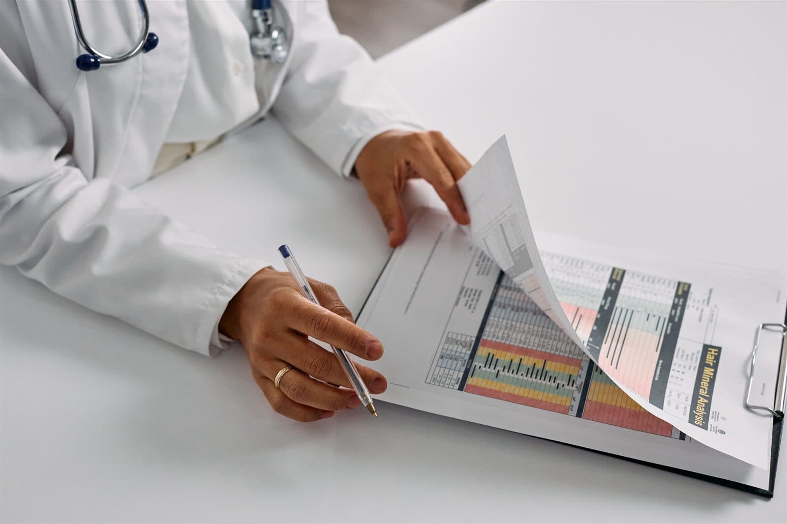 Médico revisa um relatório impresso de análise mineral capilar, com gráficos e indicadores.